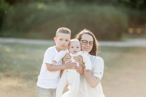 Genç ve güzel bir aile parkta yürüyor. Gün batımında aile portresi. Yaz pikniği. — Stok fotoğraf