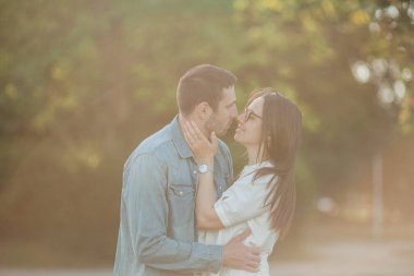 Güneş ışınları altında güzel genç bir çift. Genç ve güzel bir çift parkta yürüyor..