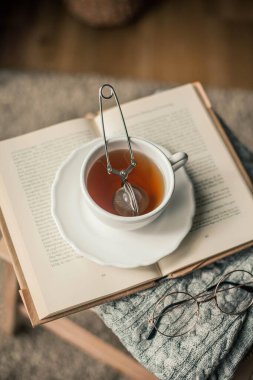 Tonlu fotoğraf. Sonbahar dekoru. Bir kupa sıcak çay, örgü süveter, kitap, bardak. Samimi. Sonbahar. Sonbahar havası.