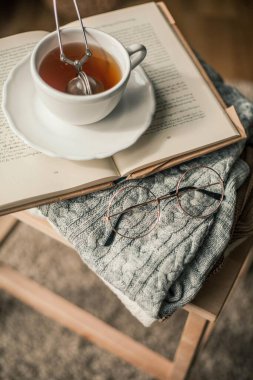 Tonlu fotoğraf. Sonbahar dekoru. Bir kupa sıcak çay, örgü süveter, kitap, bardak. Samimi. Sonbahar. Sonbahar havası.