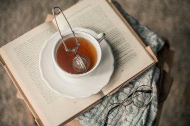 Tonlu fotoğraf. Sonbahar dekoru. Bir kupa sıcak çay, örgü süveter, kitap, bardak. Samimi. Sonbahar. Sonbahar havası.