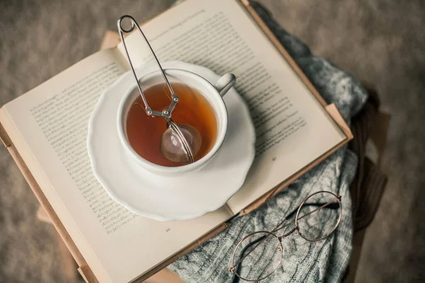 Tonlu fotoğraf. Sonbahar dekoru. Bir kupa sıcak çay, örgü süveter, kitap, bardak. Samimi. Sonbahar. Sonbahar havası.