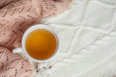 Bir kupa sıcak çay, pamuk örülmüş battaniye üzerine örülmüş süveter. Sıcak sonbahar.