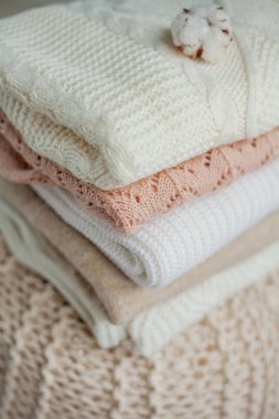 Bir yığın örgü kazak, pamuk. Kadın kazakları kanepenin üzerinde yatıyor. Sıcak sonbahar giysileri.