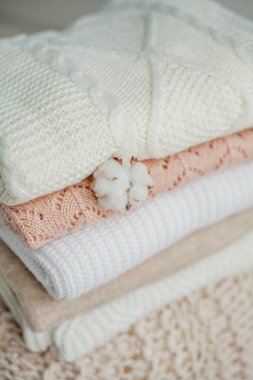 Bir yığın örgü kazak, pamuk. Kadın kazakları kanepenin üzerinde yatıyor. Sıcak sonbahar giysileri.