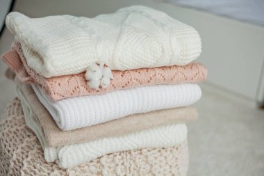 Bir yığın örgü kazak, pamuk. Kadın kazakları kanepenin üzerinde yatıyor. Sıcak sonbahar giysileri.