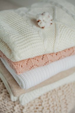 Bir yığın örgü kazak, pamuk. Kadın kazakları kanepenin üzerinde yatıyor. Sıcak sonbahar giysileri.