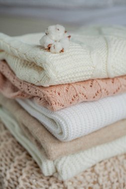 Bir yığın örgü kazak, pamuk. Kadın kazakları kanepenin üzerinde yatıyor. Sıcak sonbahar giysileri.