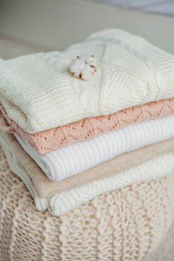 Bir yığın örgü kazak, pamuk. Kadın kazakları kanepenin üzerinde yatıyor. Sıcak sonbahar giysileri.