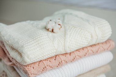 Bir yığın örgü kazak, pamuk. Kadın kazakları kanepenin üzerinde yatıyor. Sıcak sonbahar giysileri.