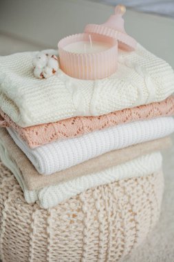 Bir yığın örgü kazak, pamuk, cam kavanozda bir mum. Kadın bluzları kanepenin üzerinde. Sıcak sonbahar kıyafetleri. Düş.