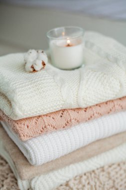 Bir yığın örgü kazak, pamuk, mum. Kadın bluzları kanepenin üzerinde. Sıcak sonbahar giysileri.