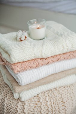 Bir yığın örgü kazak, pamuk, mum. Kadın bluzları kanepenin üzerinde. Sıcak sonbahar giysileri.