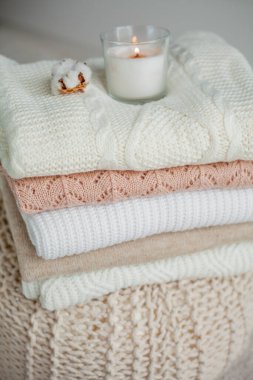 Bir yığın örgü kazak, pamuk, mum. Kadın bluzları kanepenin üzerinde. Sıcak sonbahar giysileri.