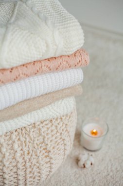 Bir yığın örgü kazak, pamuk, mum. Kadın bluzları kanepenin üzerinde. Sıcak sonbahar giysileri.