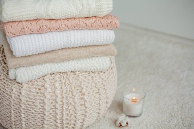 Bir yığın örgü kazak, pamuk, mum. Kadın bluzları kanepenin üzerinde. Sıcak sonbahar giysileri.