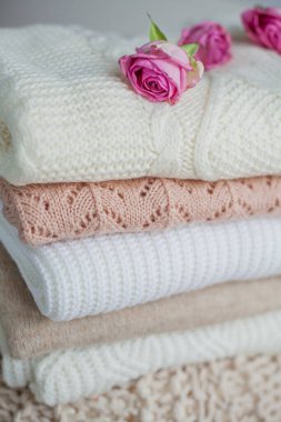 Bir yığın örgü süveter, güller. Kadın kazakları kanepenin üzerinde yatıyor. Sıcak sonbahar giysileri.