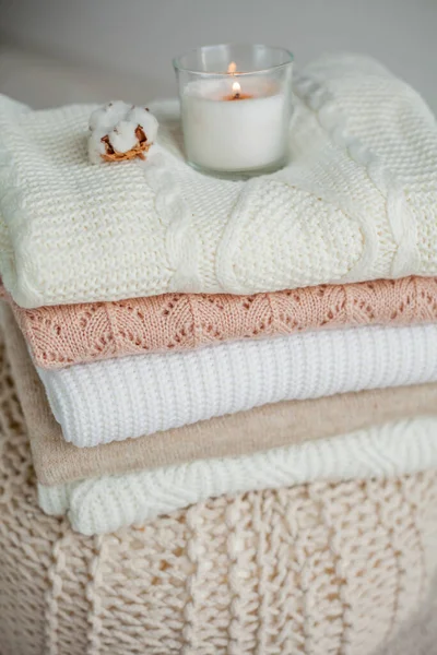 Bir yığın örgü kazak, pamuk, mum. Kadın bluzları kanepenin üzerinde. Sıcak sonbahar giysileri.