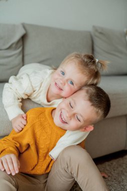 Samimi örgü süveter giyen kız ve erkek kardeşler evde oynuyorlar. Sevimli erkek ve kız kardeşlerin portresi.