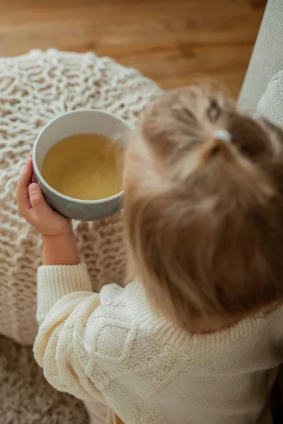 オレンジのセーターを着た可愛い女の子がお茶を飲んでいます 家に座っている女の子の居心地の良い肖像画 — ストック写真