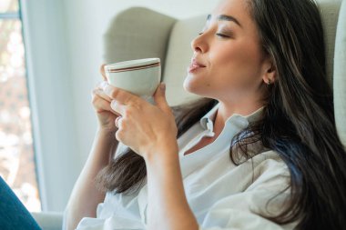 Bir battaniye ve bir fincan sıcak çayla rahat bir sandalyede 40 'lı yaşlarda Asyalı bir kadının portresi. Sonbahar evi.