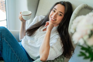 Bir battaniye ve bir fincan sıcak çayla rahat bir sandalyede 40 'lı yaşlarda Asyalı bir kadının portresi. Sonbahar evi.