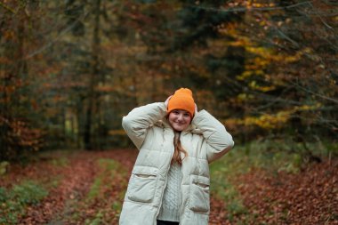 Sonbahar ormanında şapkalı ve kalın elbiseli genç bir kızın portresi. Doğada meditasyon.