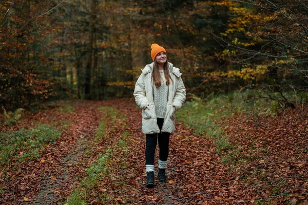 Sonbahar ormanında şapkalı ve kalın elbiseli genç bir kızın portresi. Doğada meditasyon.
