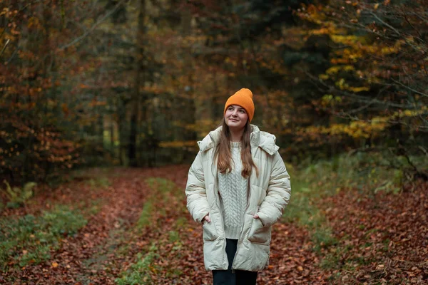 Sonbahar ormanında şapkalı ve kalın elbiseli genç bir kızın portresi. Doğada meditasyon.