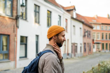 Sonbahar kıyafetleri içinde sakallı bir adamın portresi. Eski bir Avrupa şehrinde sırt çantalı bir turist.