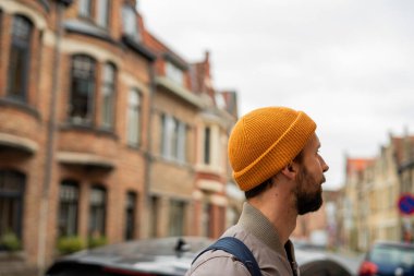 Sonbahar kıyafetleri içinde sakallı bir adamın portresi. Eski bir Avrupa şehrinde sırt çantalı bir turist.