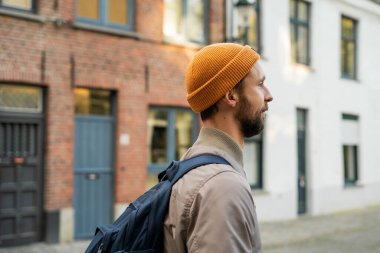 Sonbahar kıyafetleri içinde sakallı bir adamın portresi. Eski bir Avrupa şehrinde sırt çantalı bir turist.