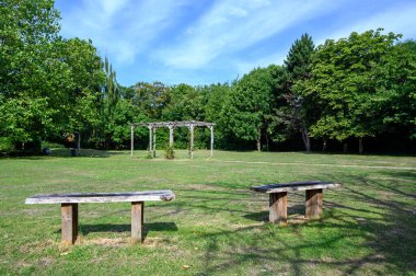 Bromley 'de üniversite yeşili, Kent. Bromley 'nin merkezine yakın bu açık alanda çimen alanları, çiçekler ve ağaçlar var. Fotoğrafta koltuklar ve pergola var. Bromley İlçesi Londra 'nın en büyük ilçesidir..  