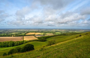 South Downs Ulusal Parkı, Sussex, İngiltere Firle Beacon yakınlarında. Güney Downs Yolu 'ndan görünen güneş ışığı ve bulutlarla Weald' a bakıyor. South Downs Yolu, aylaklar arasında popüler olan ulusal bir patikadır..