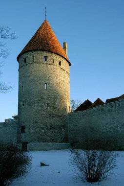 Tallinn, Estonya şehir duvarında bir savunma kulesi. Alçak güneşin uzun gölgeler bıraktığı kış sahnesi. Şehir duvarı ortaçağ Tallinn Eski Kasabasını koruyor..