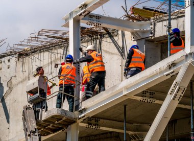 Bükreş / Romanya - 05.16.2020: Güvenlik ekipmanı takan inşaat işçileri. İnşaat şantiyesinde çalışan erkekler.