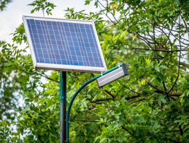 Fotovoltaik panelli sokak aydınlatma direği ve yeşil arka planlı LED lamba ışıkları