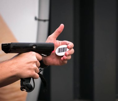 Eller tarayıcıyı tutuyor ve barkodu tarıyor.