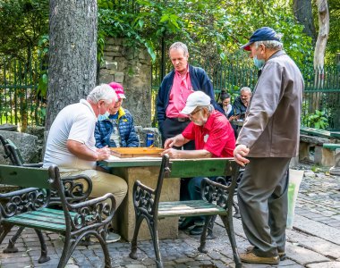 Bükreş / Romanya - 05.30.2020: Bükreş 'teki Cismigiu parkında tavla oynayan yaşlılar. Yaşlı adamlar parkta oyun oynuyorlar..