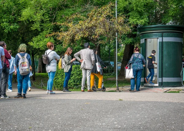 Bükreş / Romanya - 05.30.2020: Cismigiu parkındaki umumi mobil tuvaleti kullanmak için sırada bekleyen insanlar.