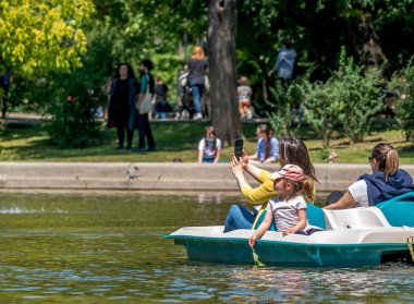 Bükreş / Romanya - 05.30.2020: Coronavirus salgınından sonra kalabalık park. Annem ve çocuklar Cismigiu parkında bir teknede..