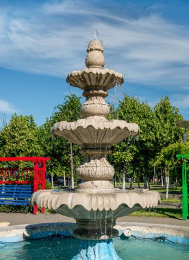 Bükreş 'teki Çocuk Dünyası Parkı' nda mermer ya da taş çeşme. Su çeşmesi açık mavi gökyüzüne karşı.