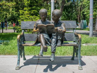 Bükreş / Romanya - 05.30.2020: Bankta kitap okuyan bir kız ve erkek çocuğunun bronz heykeli.