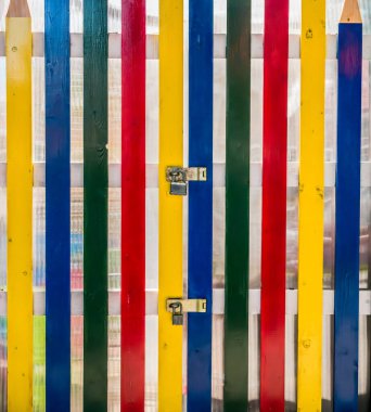 Renkli ahşap kalemlerden yapılmış kilitli kapısı olan bir çit..