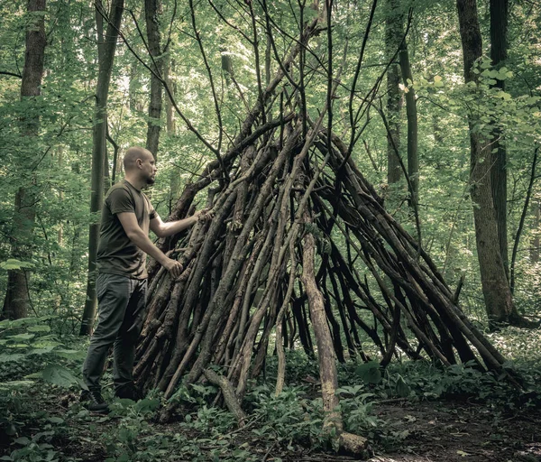 Man building a survival shelter in the forest. Shelter in the woods from tree branches.