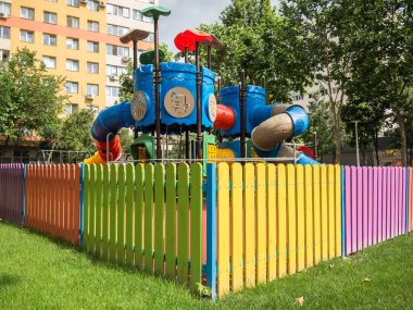 Bükreş / Romanya - 06.22.2020: Renkli ahşap çitlerle çevrili apartmanlar arasında küçük çocuklar parkı.