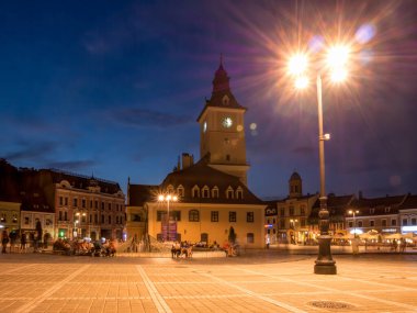 Brasov / Romanya - 06.28.2020: Brasov belediye binası eski belediye meclisi meydanında yer alıyor. Brasov 'un ana meydanı gün batımında ya da gece.