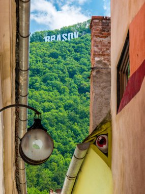 Brasov / Romanya - 06.28.2020: Brasov Tampa Dağı 'nda büyük harflerle yazıldı. Eski şehrin dar sokaklarından Brasov tabelası görünüyor..