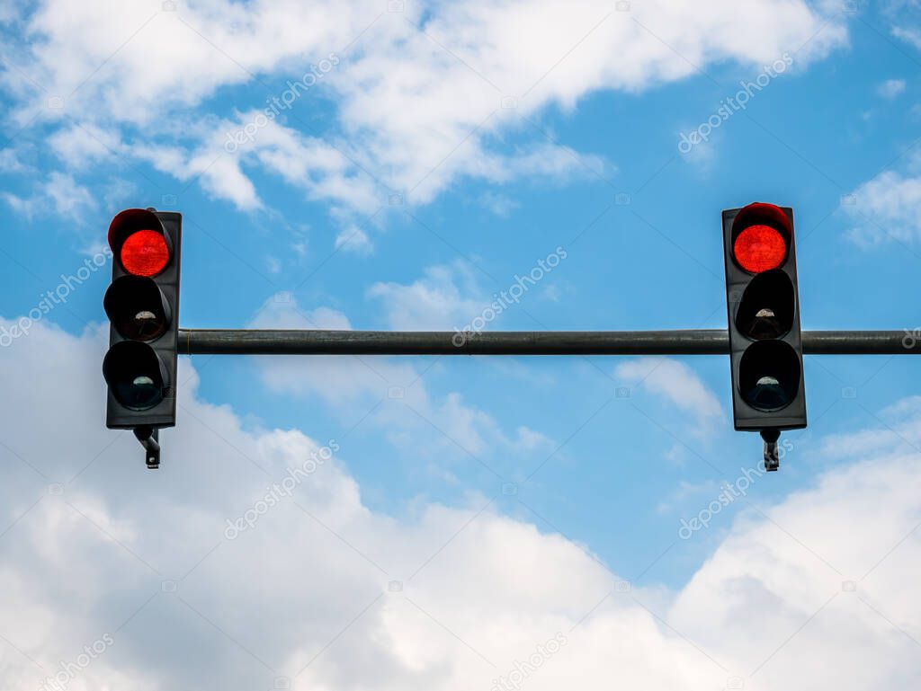 Two traffic lights showing red color against blue sky.