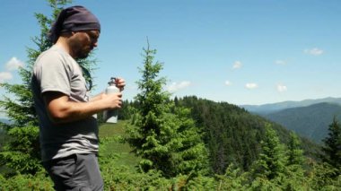 Su şişesinden su içen yorgun bir yürüyüşçü..